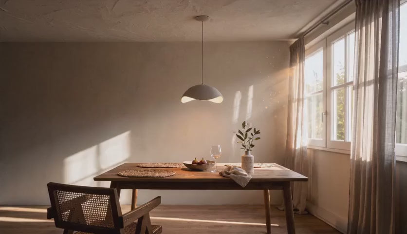 Charger la vidéo : Cinematic video of an asymmetric dome pendant lamp glowing warmly above a wooden dining table in soft afternoon light.
