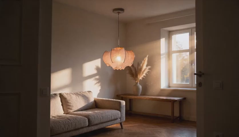 Charger la vidéo : Cinematic video of a draped petal cocoon pendant glowing warmly above a linen sofa in a sunlit living room.